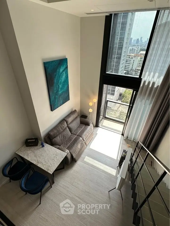 Modern loft apartment with high ceilings and city view, featuring stylish decor and natural light.
