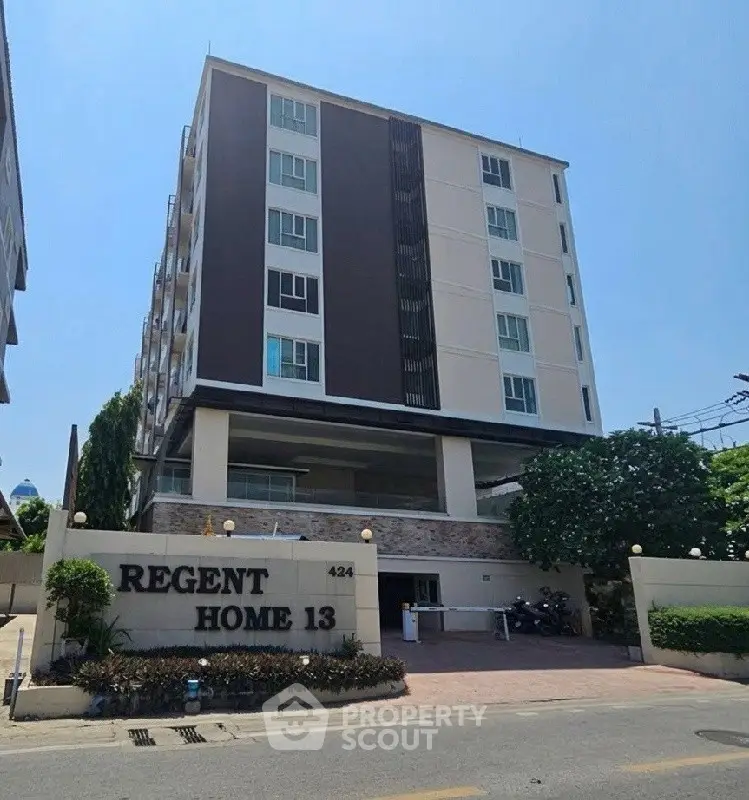 Modern multi-story residential building with secure entrance and lush landscaping.