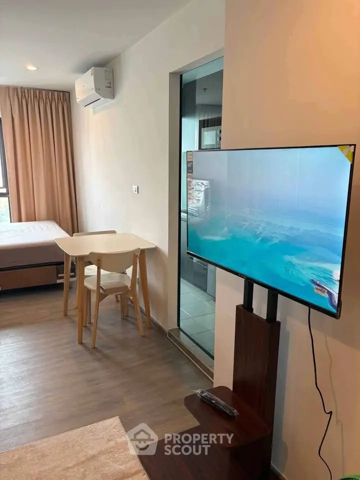 Modern studio apartment with TV, dining table, and air conditioning, featuring a sleek design and natural light.