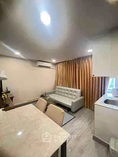 Modern living room with elegant decor and open kitchen layout, featuring a cozy sofa and dining area.