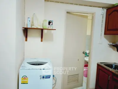 Compact kitchen area with washing machine and wooden cabinets