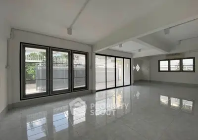 Spacious modern living room with large windows and glossy tiled floors, perfect for natural light lovers.