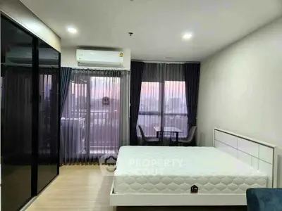 Modern bedroom with city view, featuring large windows and sleek furnishings.