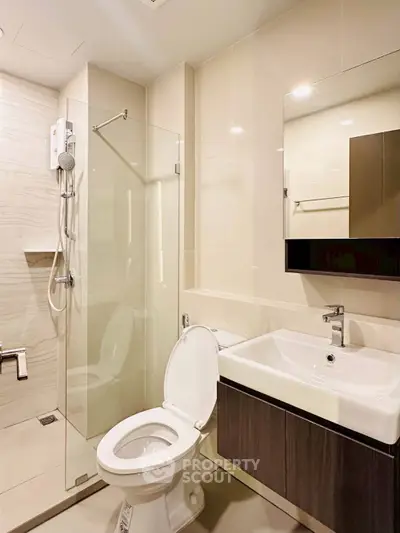 Modern bathroom with glass shower and sleek vanity in contemporary apartment.