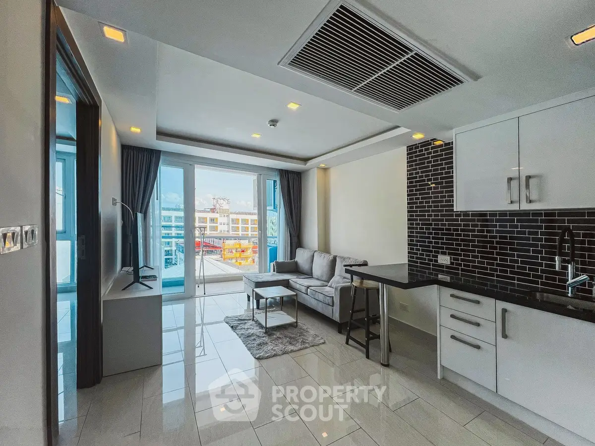 Modern living room with sleek kitchen and city view, featuring stylish black backsplash and cozy seating area.
