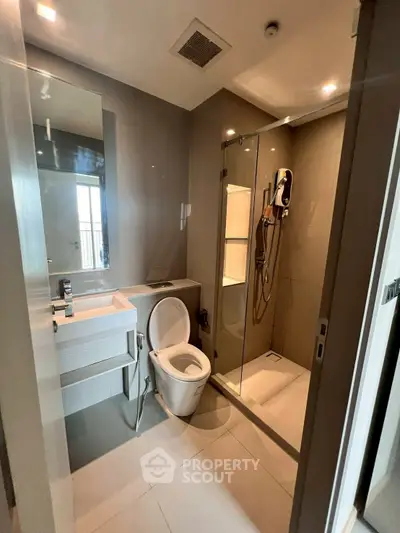 Modern bathroom with glass shower and sleek fixtures in contemporary apartment.