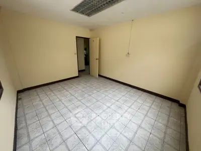Spacious empty room with tiled flooring and neutral walls, ideal for customization.