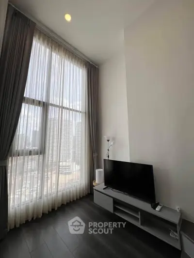 Modern living room with high ceilings and large windows offering city views.