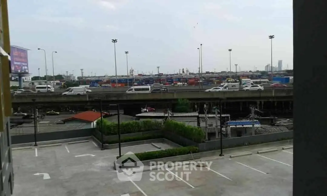 Urban view from a parking area overlooking a busy highway and cityscape.