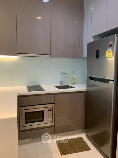 Modern kitchen with sleek cabinets, built-in microwave, and stainless steel fridge