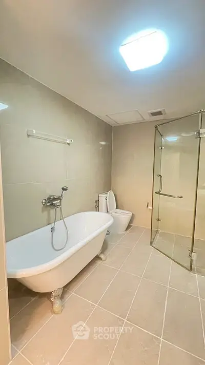 Spacious bathroom with elegant bathtub and glass shower enclosure