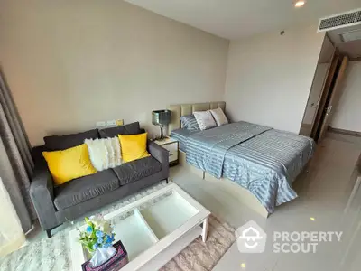 Modern bedroom with cozy seating area and stylish decor, featuring a plush bed and vibrant cushions.