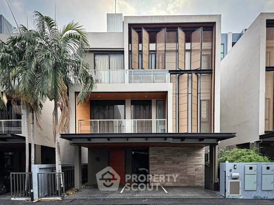 Modern architectural facade of a luxury townhouse with sleek design and palm trees.