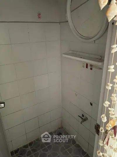 Compact bathroom with tiled walls and minimal fixtures, ideal for renovation.