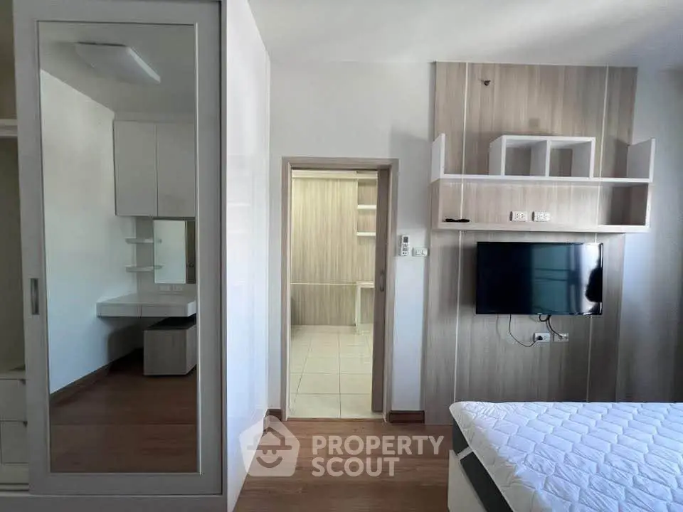 Modern bedroom with sleek design, wall-mounted TV, and ample storage space.