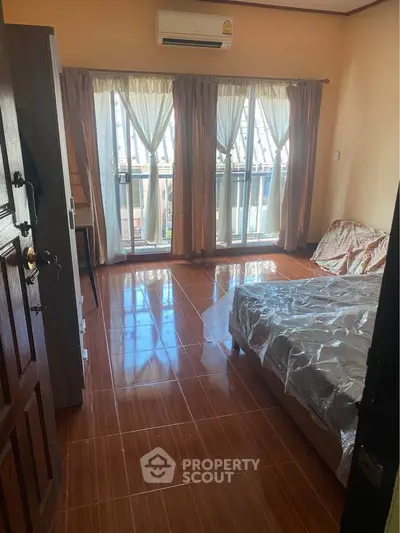 Spacious bedroom with large windows and wooden flooring, perfect for natural light lovers.