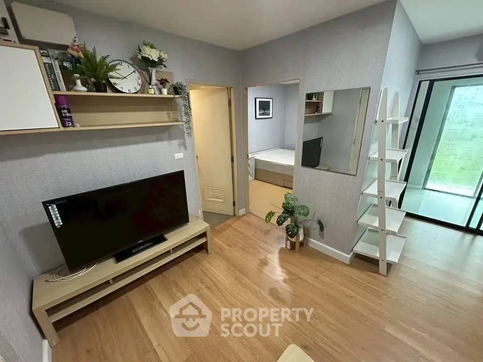 Modern living room with wooden flooring, TV, and stylish shelving in a cozy apartment.