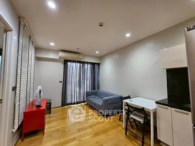 Modern living room with hardwood floors, cozy sofa, and compact dining area in a stylish apartment.
