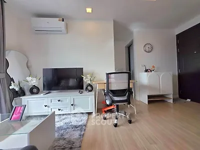 Modern living room with stylish decor, featuring a TV, air conditioning, and a cozy workspace.