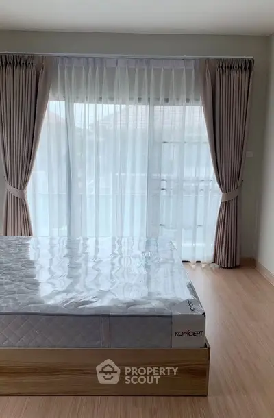 Spacious bedroom with large window and elegant curtains