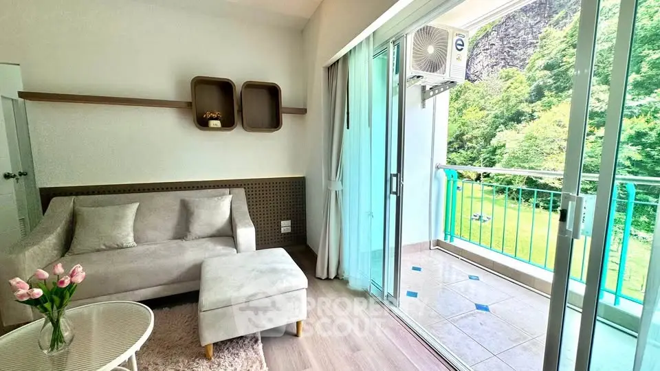 Charming living room with cozy sofa and access to a scenic balcony view.