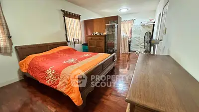 Spacious bedroom with wooden furniture and vibrant bedding in a cozy home setting.
