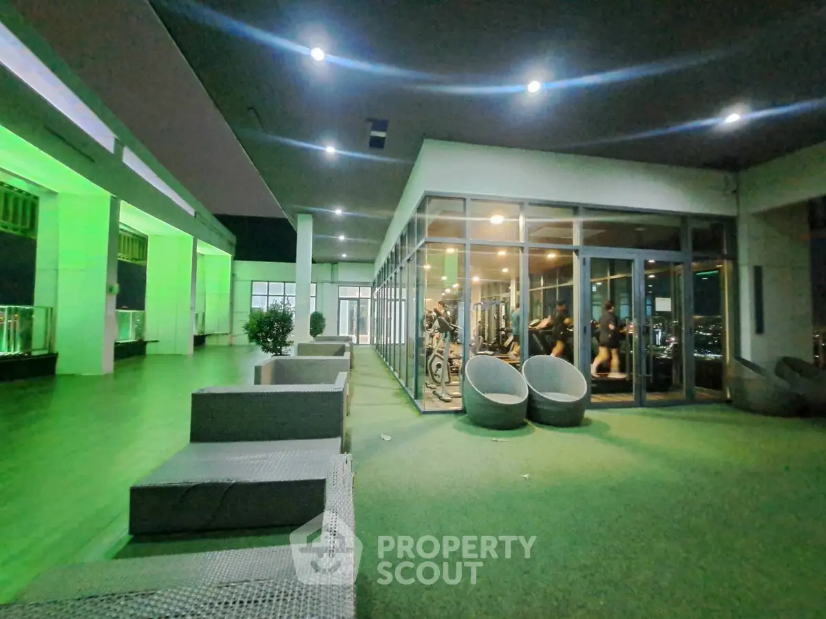 Modern gym with glass walls and outdoor seating area in luxury apartment complex