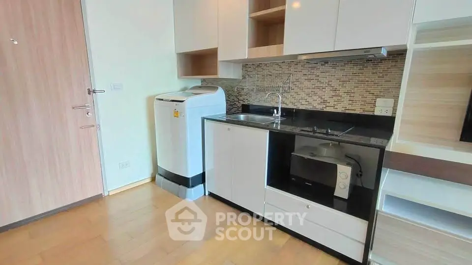 Modern compact kitchen with washing machine and microwave in stylish apartment