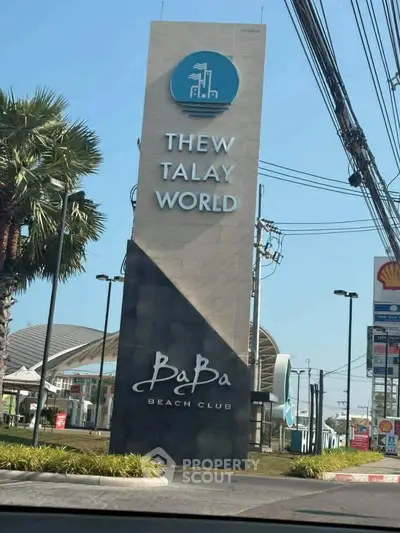 Entrance sign of Thew Talay World Baba Beach Club with modern design and palm trees.