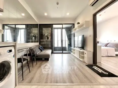 Modern living room with sleek furniture and washing machine, open layout leading to a cozy bedroom.