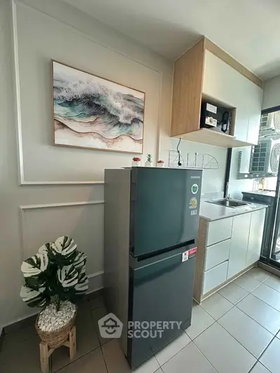 Modern kitchen with sleek fridge and stylish cabinetry, perfect for urban living.