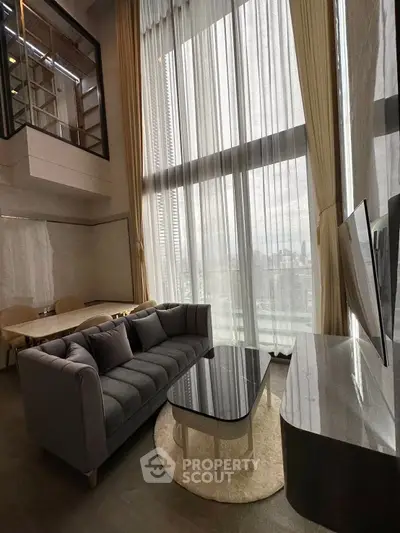 Luxurious high-ceiling living room with floor-to-ceiling windows and modern furnishings.