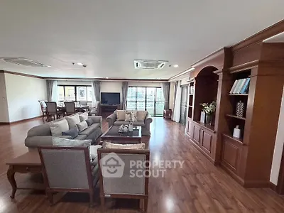 Spacious living room with elegant wooden flooring and classic furniture, perfect for family gatherings.