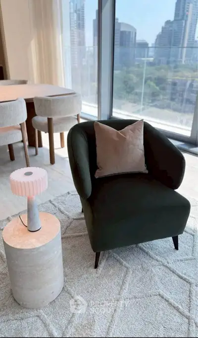 Modern living room with stylish armchair and city view from large windows.