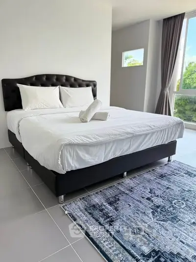 Spacious bedroom with modern decor and large window offering natural light.