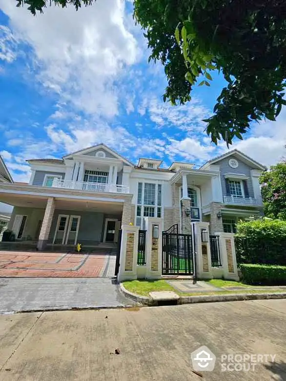 Stunning two-story house with elegant facade and spacious driveway under a clear blue sky.