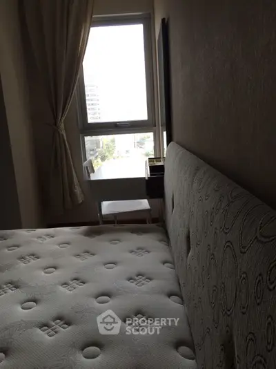 Cozy bedroom with a large window offering natural light and a comfortable bed.