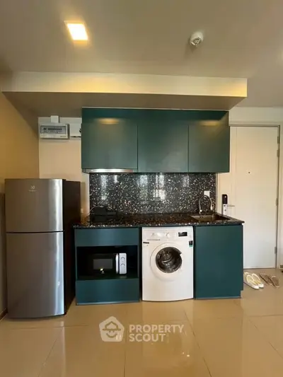 Modern kitchen with sleek appliances including washing machine and microwave, stylish cabinetry, and glossy tiled floor.