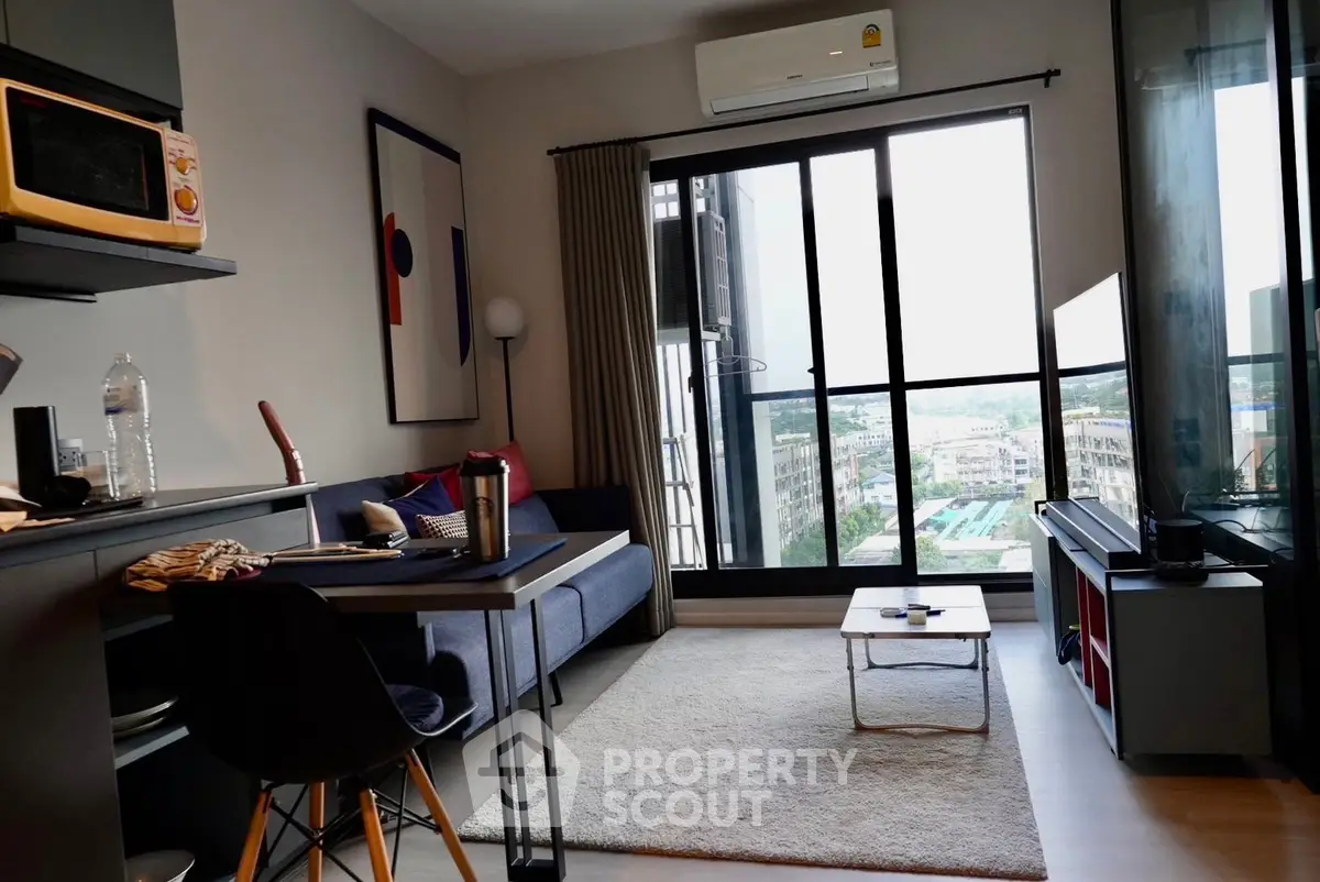 Modern living room with balcony view, stylish decor, and natural light in urban apartment.