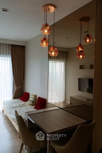 Modern living room with stylish lighting and cozy decor, featuring a comfortable seating area and large windows.