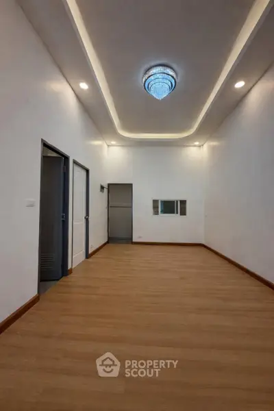 Spacious room with elegant ceiling light and wooden flooring, perfect for versatile interior design.