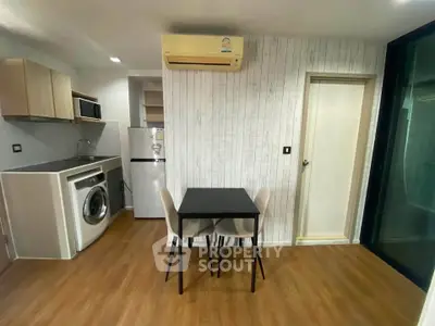 Modern compact kitchen with washing machine and dining area in stylish apartment.