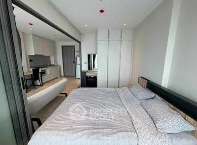 Modern bedroom with sliding doors and open kitchen layout in a stylish apartment.