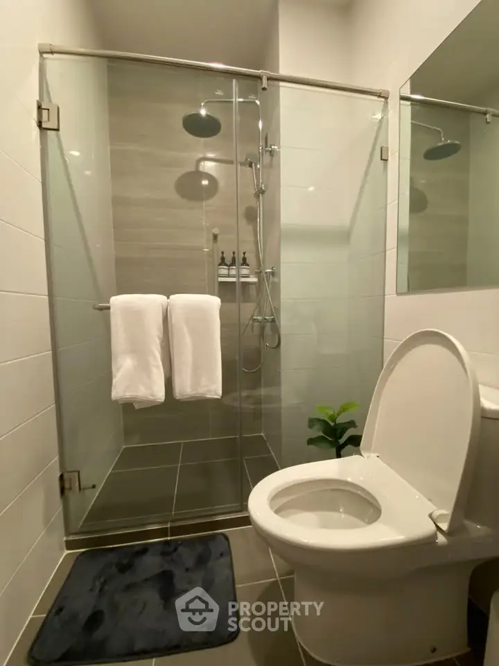 Modern bathroom with glass shower and sleek fixtures in contemporary home.