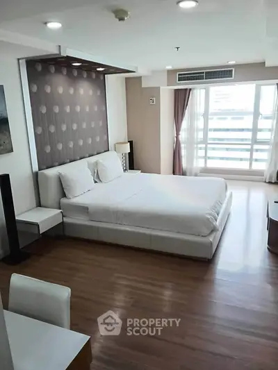 Spacious modern bedroom with large windows and stylish decor in a high-rise apartment.
