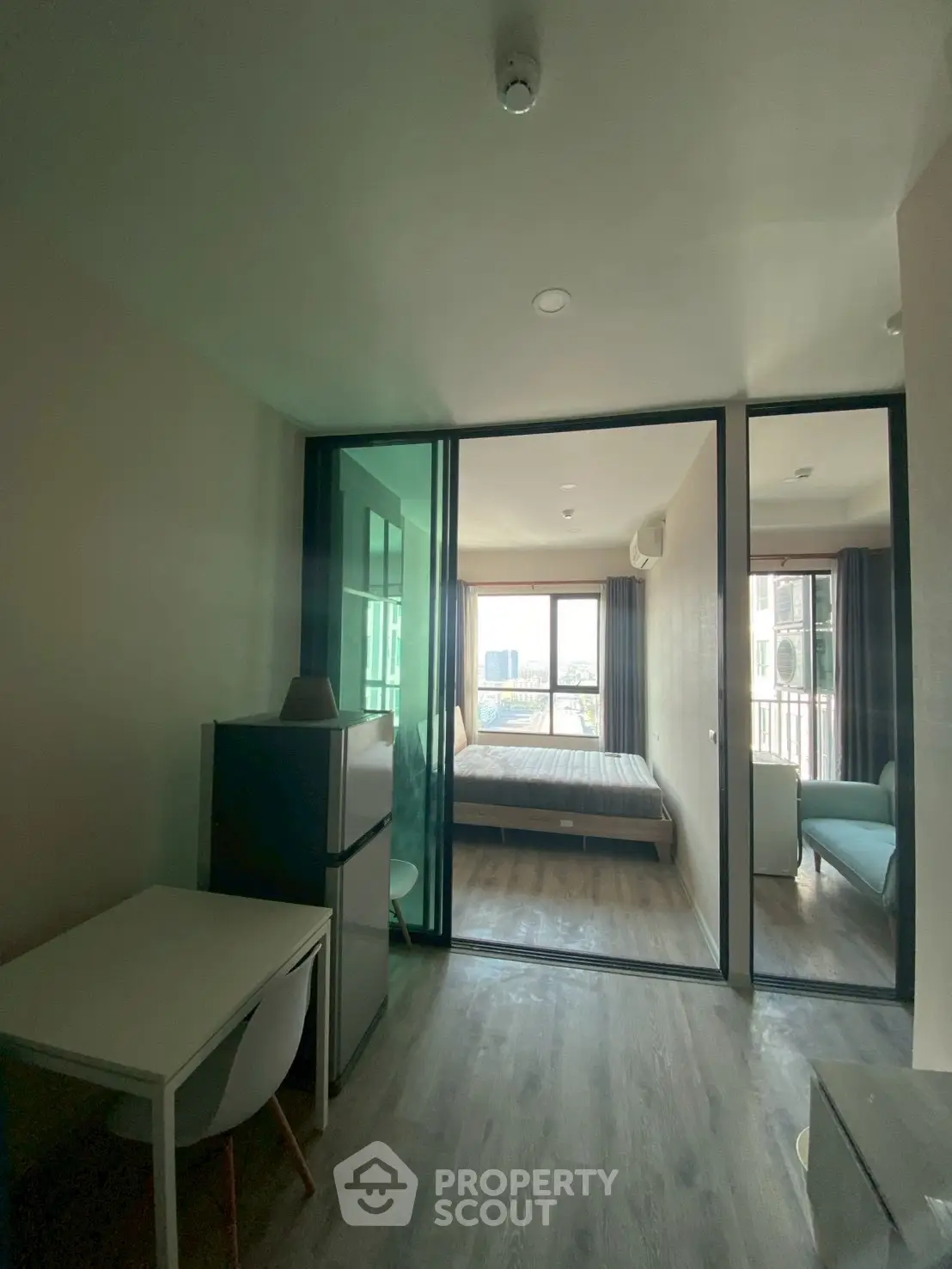 Modern apartment interior with glass partition, cozy bedroom, and city view.