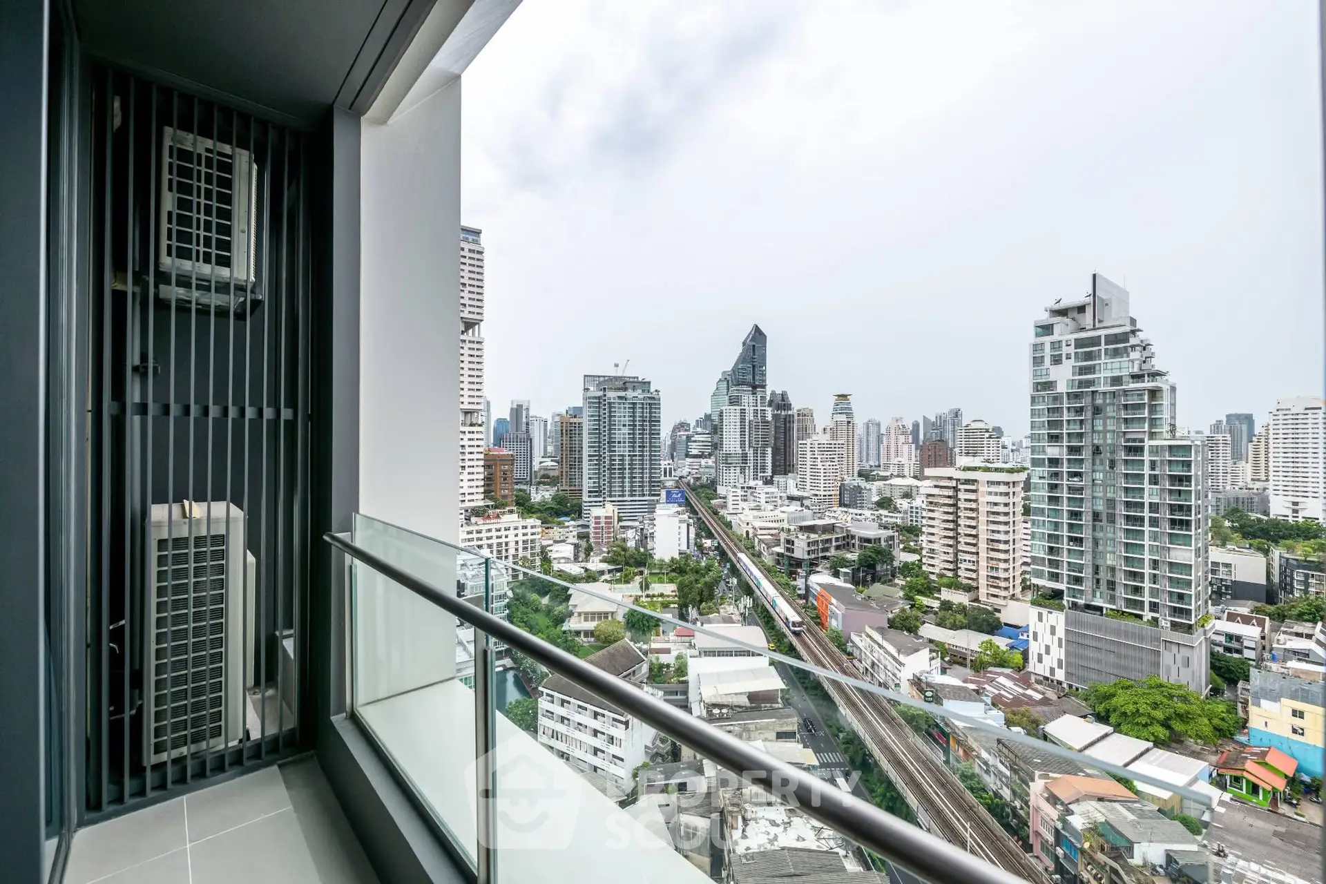 Stunning cityscape view from modern high-rise balcony with sleek glass railing.