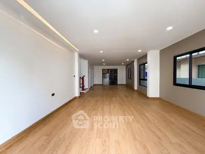 Spacious open-plan living area with wooden flooring and modern lighting, perfect for family gatherings.