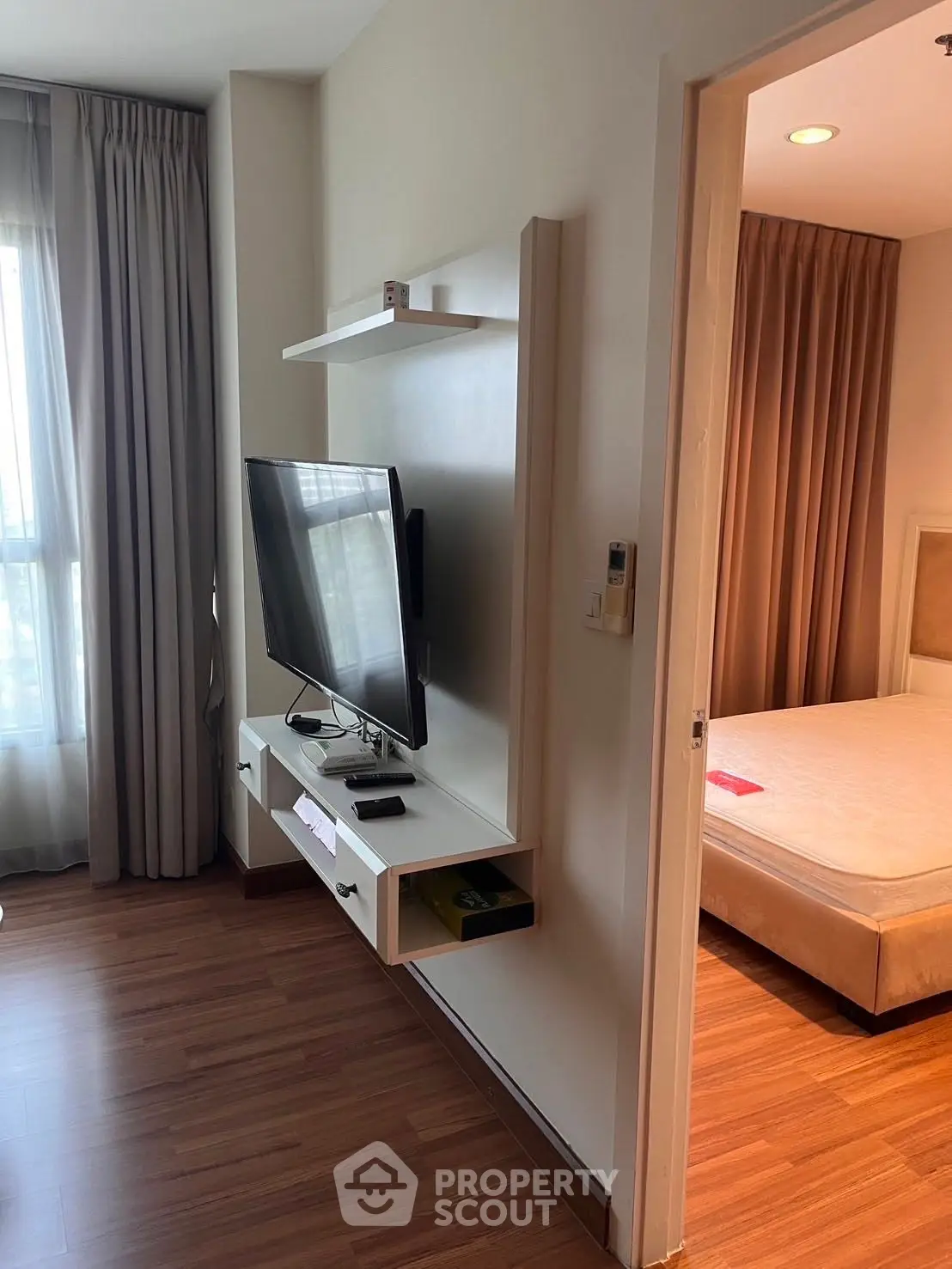 Modern apartment interior with sleek TV setup and cozy bedroom view