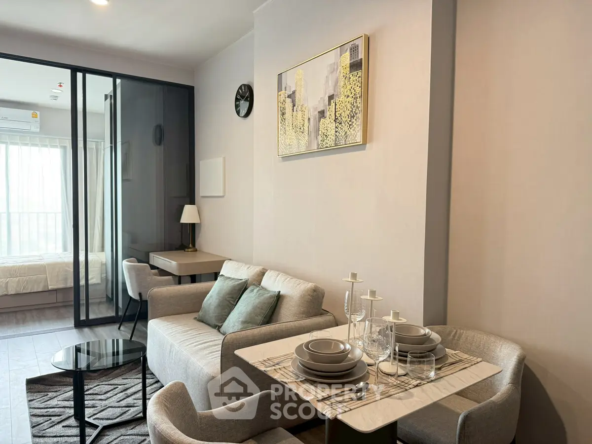 Modern living room with dining area and glass partition leading to bedroom, featuring elegant decor.